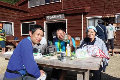 黒部五郎小屋前のベンチで乾杯している写真