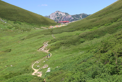 コルに立つ双六小屋と鷲羽岳の写真