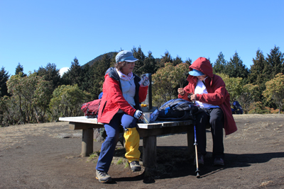 山頂のベンチに座って昼食中のＳさんとＴさんの写真