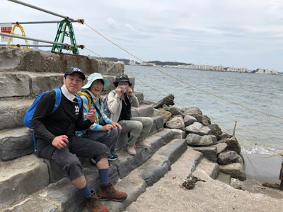 海のそばにいるメンバー３人の写真