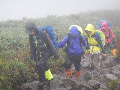 風雨の強い岩ごろの道を歩いている写真