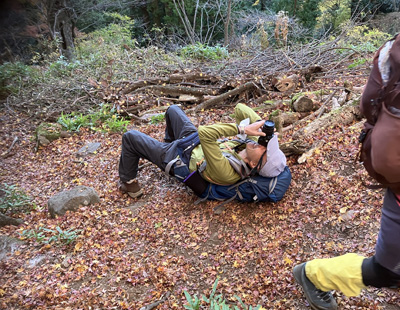 寝そべって真上の紅葉の写真を撮っているAさんの写真